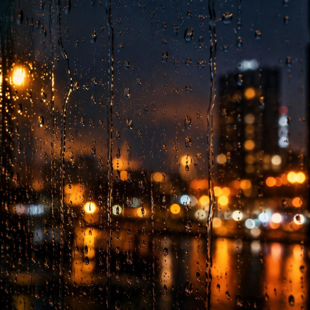 Raindrops on a window with blurred city lights behind